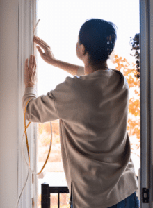 adding weather stripping to seal air leaks around a door